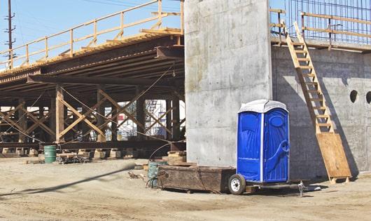 a row of sturdy portable toilets at a construction site